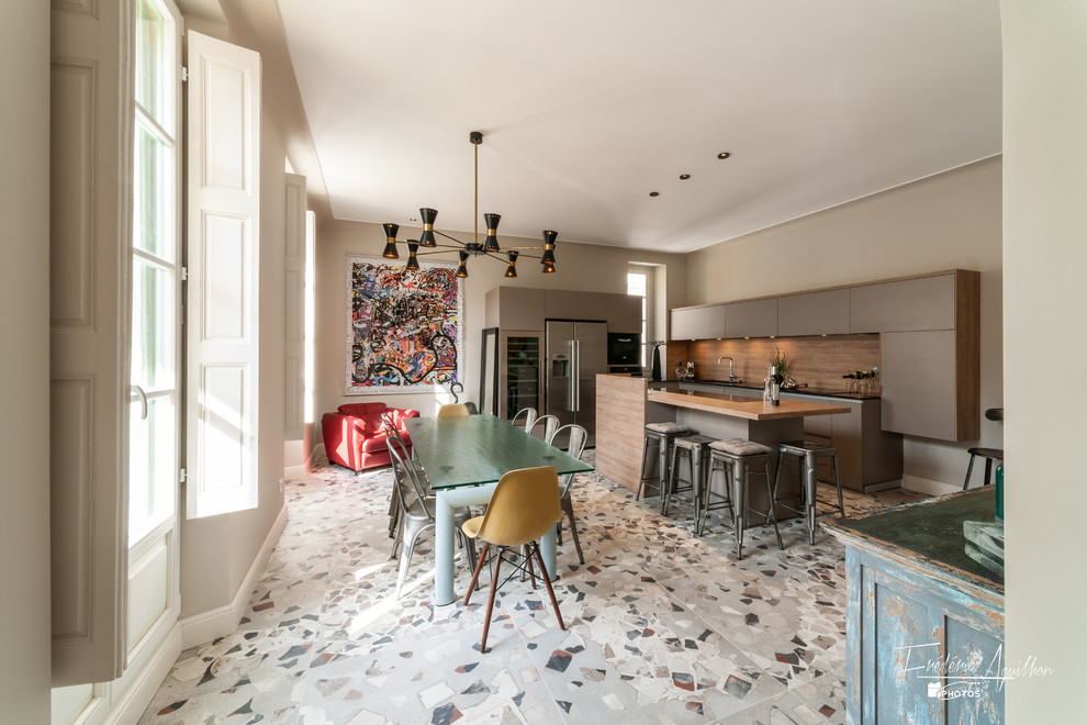 This is an example of a large contemporary u-shaped eat-in kitchen in Nice with an undermount sink, beaded inset cabinets, grey cabinets, quartz benchtops, brown splashback, timber splashback, stainless steel appliances, cement tiles, with island, multi-coloured floor and black benchtop.
