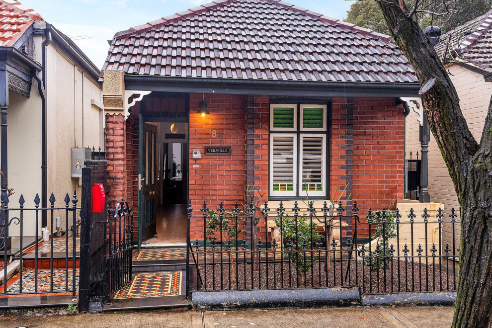 Photo of a small traditional two-storey brick red house exterior in Sydney with a hip roof, a tile roof and a red roof.