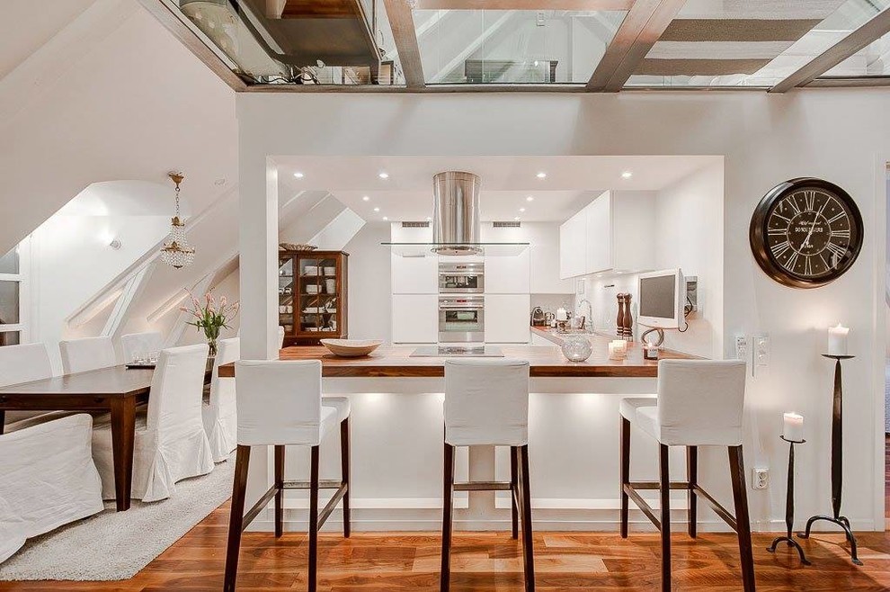 Large transitional l-shaped eat-in kitchen in Other with flat-panel cabinets, white cabinets, wood benchtops, white splashback, white appliances, medium hardwood floors and a peninsula.