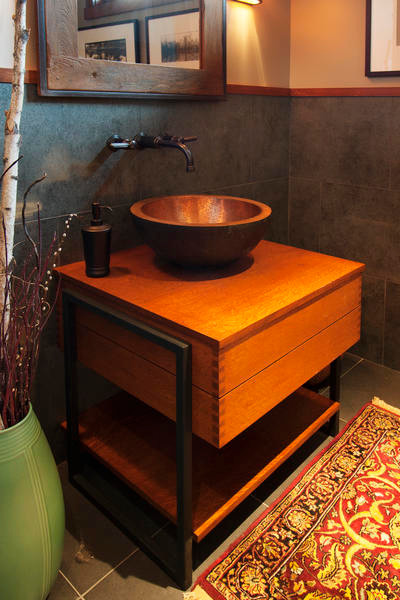 This is an example of a mid-sized arts and crafts powder room in Other with furniture-like cabinets, orange cabinets, gray tile, porcelain tile, beige walls, porcelain floors, a vessel sink, wood benchtops and grey floor.
