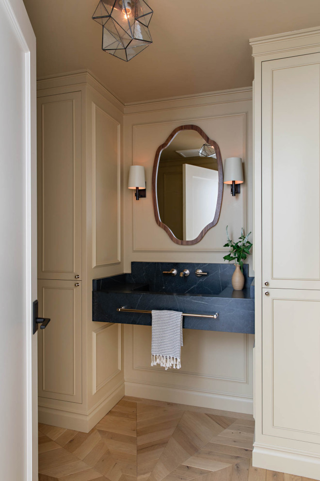 Immagine di un bagno di servizio stile marino con pareti beige, parquet chiaro, lavabo sospeso, top in marmo, top nero e pannellatura