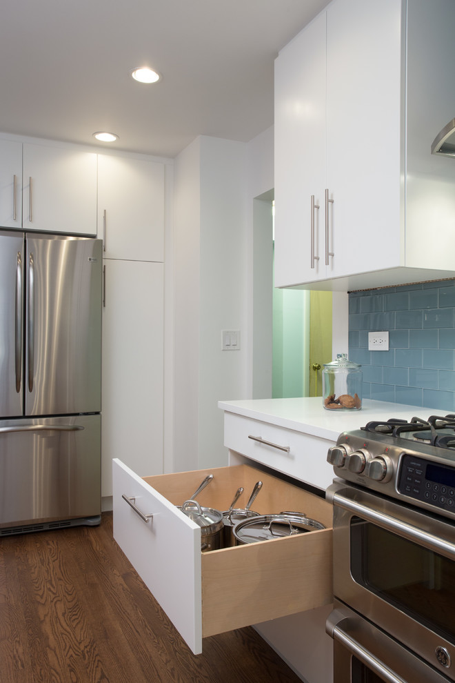 Design ideas for a mid-sized modern galley eat-in kitchen in Chicago with an undermount sink, flat-panel cabinets, white cabinets, blue splashback, subway tile splashback, stainless steel appliances, medium hardwood floors, no island and quartz benchtops.