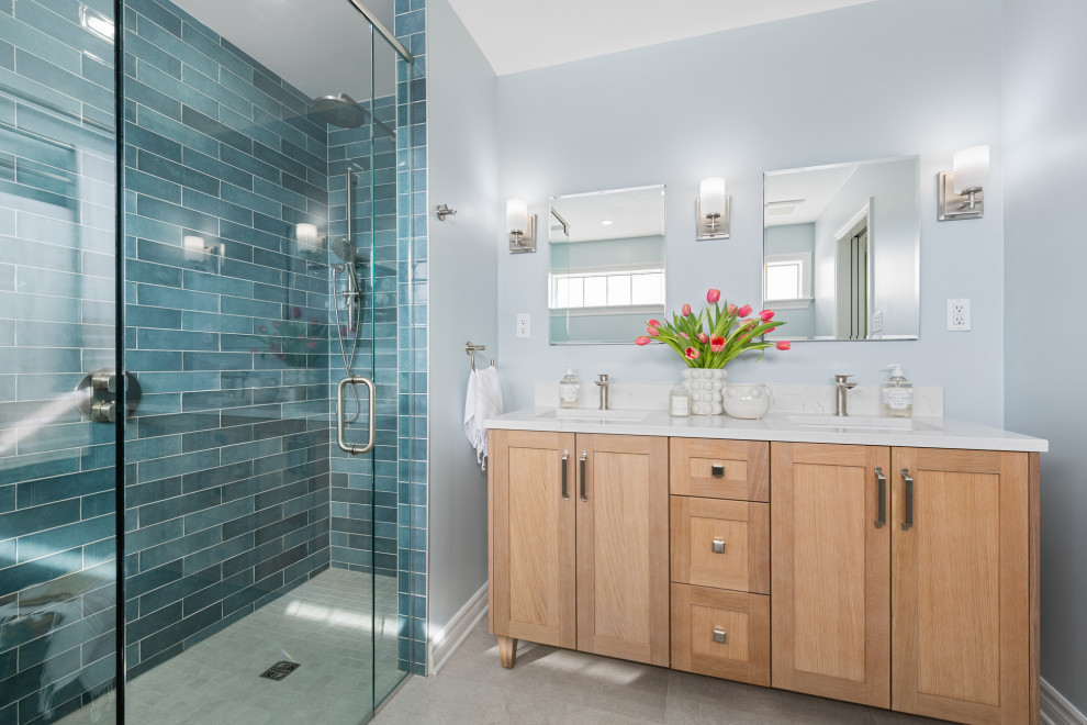 Large beach style master blue tile and ceramic tile ceramic tile, double-sink and blue floor bathroom photo in Ottawa with shaker cabinets, light wood cabinets, a two-piece toilet, blue walls, an undermount sink, a hinged shower door, white countertops, a niche, a freestanding vanity and quartz countertops