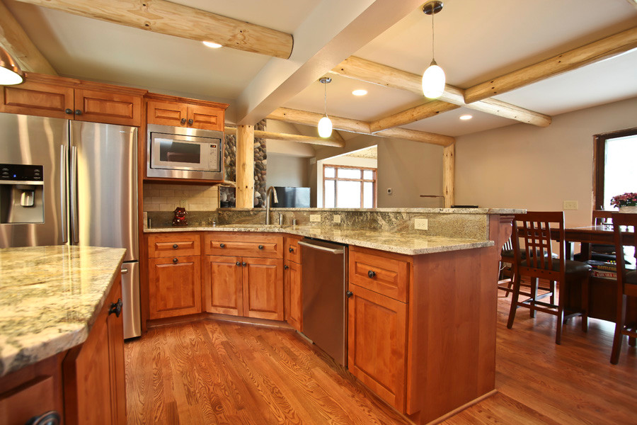 Inspiration for a large rustic u-shaped medium tone wood floor eat-in kitchen remodel in Milwaukee with a single-bowl sink, shaker cabinets, medium tone wood cabinets, granite countertops, beige backsplash, ceramic backsplash, stainless steel appliances and an island