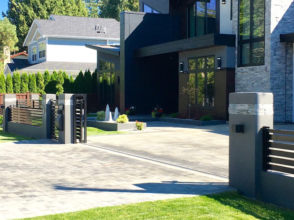 Inspiration for a large modern front yard partial sun driveway in Vancouver with concrete pavers.