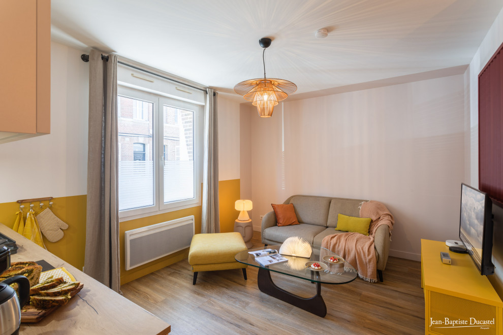 This is an example of a mid-sized scandinavian open concept living room in Paris with beige walls, laminate floors, no fireplace, a wall-mounted tv and brown floor.