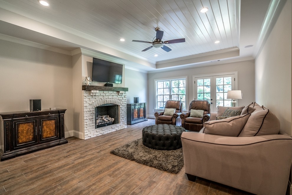This is an example of a mid-sized traditional walk-out basement in Atlanta with grey walls, ceramic floors, a standard fireplace, a brick fireplace surround and brown floor.