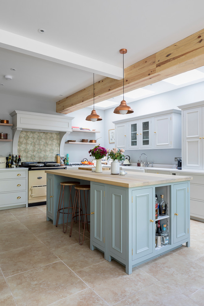Inspiration for a mid-sized country l-shaped eat-in kitchen in London with a farmhouse sink, shaker cabinets, grey cabinets, solid surface benchtops, green splashback, porcelain splashback, stainless steel appliances, limestone floors, with island and beige floor.