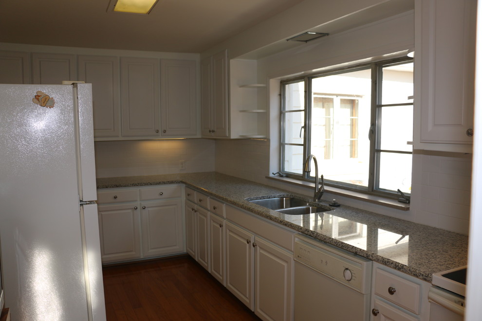Eat-in kitchen - mid-sized traditional l-shaped light wood floor eat-in kitchen idea with an undermount sink, raised-panel cabinets, white cabinets, granite countertops, white backsplash, ceramic backsplash and white appliances