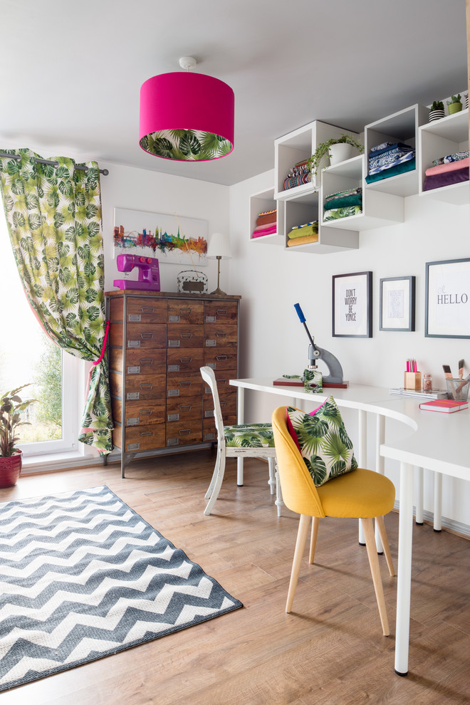 Photo of a mid-sized eclectic home studio in Edinburgh with white walls, laminate floors, no fireplace and a freestanding desk.