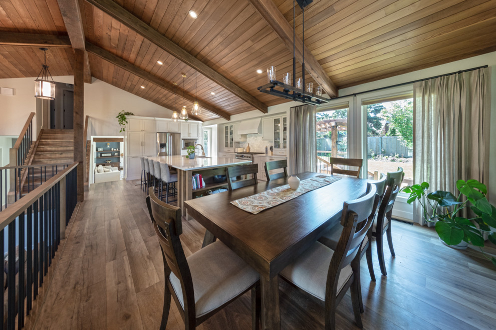 Immagine di una sala da pranzo aperta verso la cucina country di medie dimensioni con pareti bianche, pavimento in legno massello medio, pavimento marrone e soffitto a volta