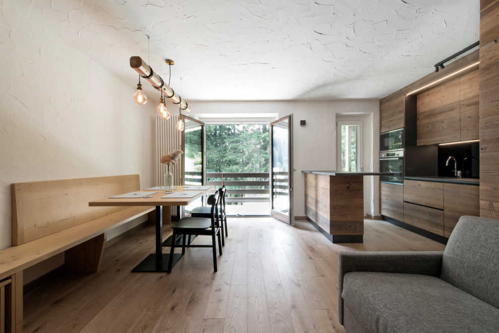 Immagine di una sala da pranzo aperta verso il soggiorno rustica di medie dimensioni con pareti bianche, pavimento in legno massello medio e pareti in legno