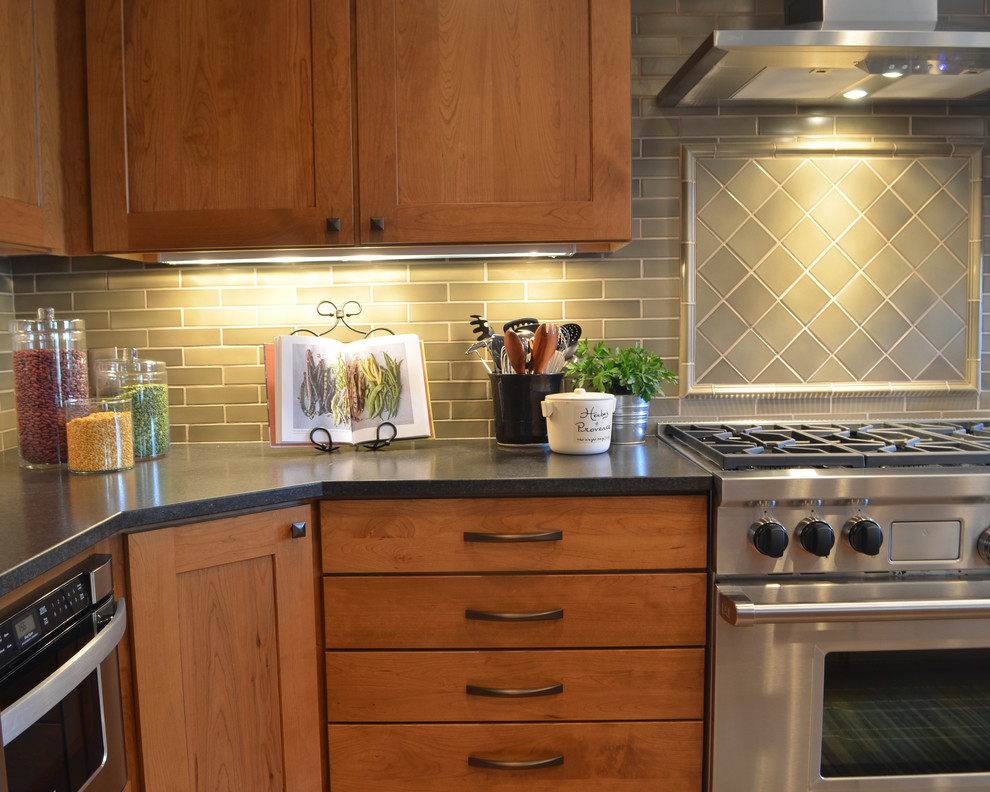 Mid-sized transitional u-shaped light wood floor eat-in kitchen photo in Denver with a single-bowl sink, shaker cabinets, medium tone wood cabinets, granite countertops, green backsplash, ceramic backsplash, stainless steel appliances and an island