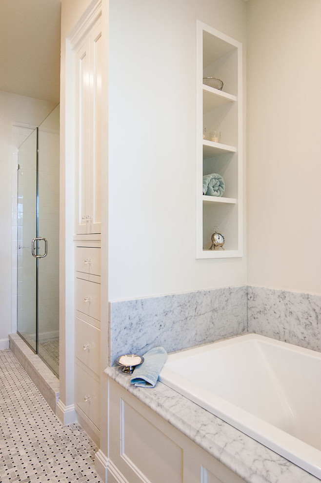 This is an example of a mid-sized transitional master bathroom in Portland Maine with an undermount sink, shaker cabinets, white cabinets, marble benchtops, a drop-in tub, an alcove shower, a two-piece toilet, mosaic tile, beige walls, mosaic tile floors, white tile, grey floor and a hinged shower door.