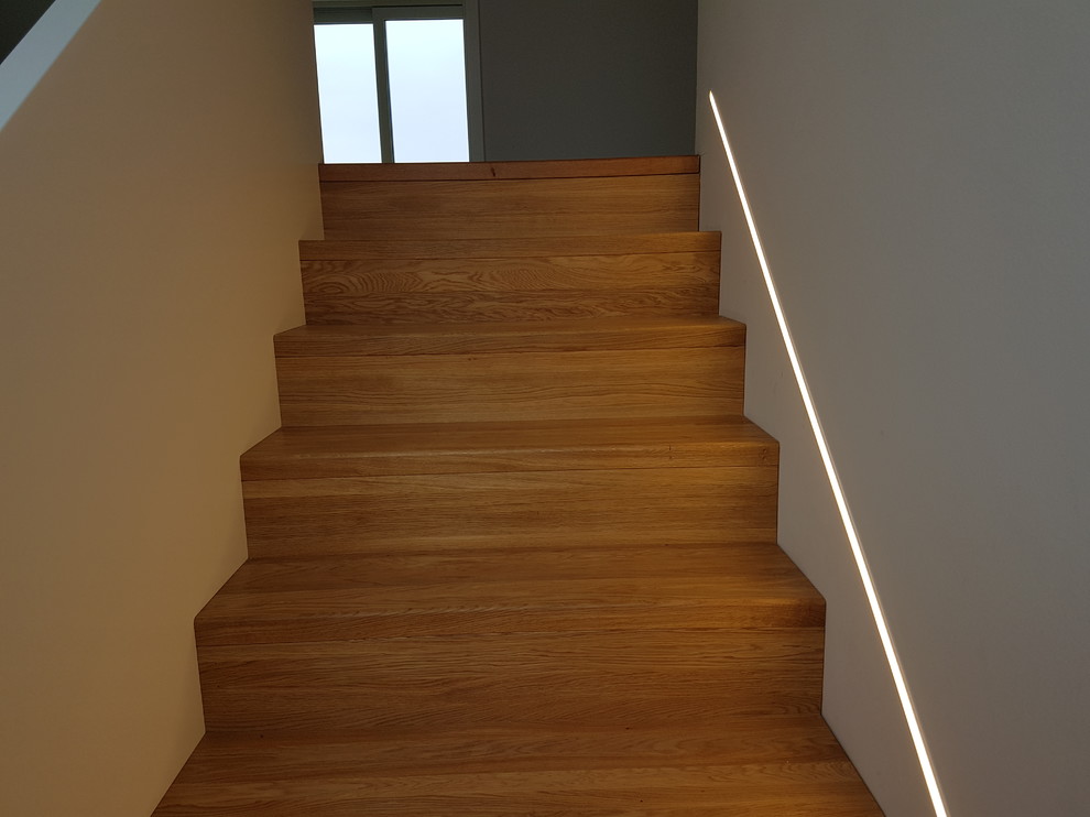 Design ideas for a large contemporary wood u-shaped staircase in Frankfurt with wood risers and wood railing.