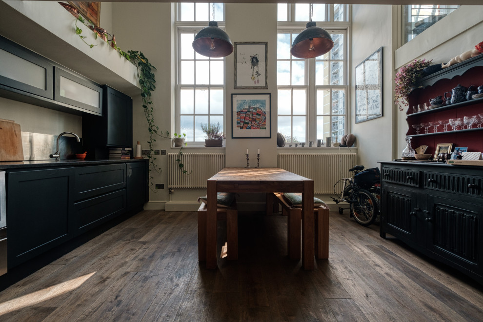Exempel på ett mellanstort industriellt svart linjärt svart kök och matrum, med en integrerad diskho, skåp i shakerstil, svarta skåp, granitbänkskiva, stänkskydd med metallisk yta, stänkskydd i metallkakel, rostfria vitvaror, mörkt trägolv och brunt golv