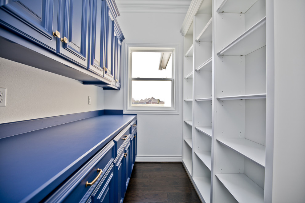 Photo of a mid-sized transitional single-wall kitchen pantry in Other with raised-panel cabinets, blue cabinets, solid surface benchtops, stainless steel appliances, dark hardwood floors, brown floor and blue benchtop.