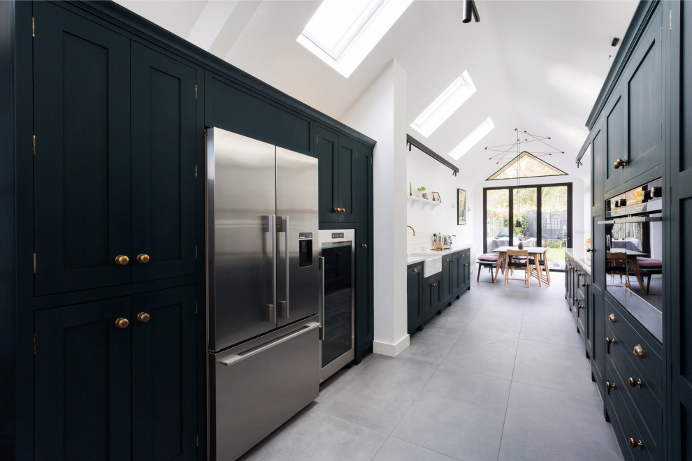Inspiration for a large contemporary galley open plan kitchen in Essex with a farmhouse sink, shaker cabinets, green cabinets, quartzite benchtops, white splashback, mosaic tile splashback, stainless steel appliances, cement tiles, no island, grey floor and white benchtop.