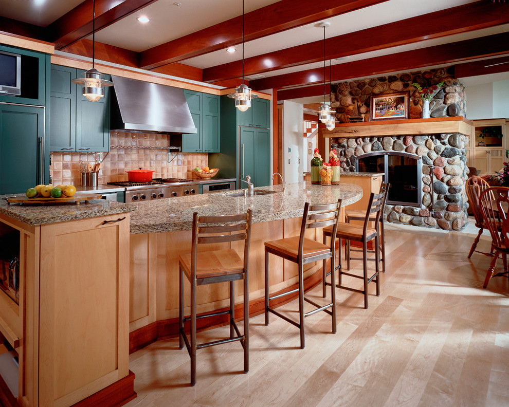 Inspiration for an eclectic single-wall open plan kitchen in Minneapolis with shaker cabinets, green cabinets, granite benchtops, stainless steel appliances, light hardwood floors and with island.
