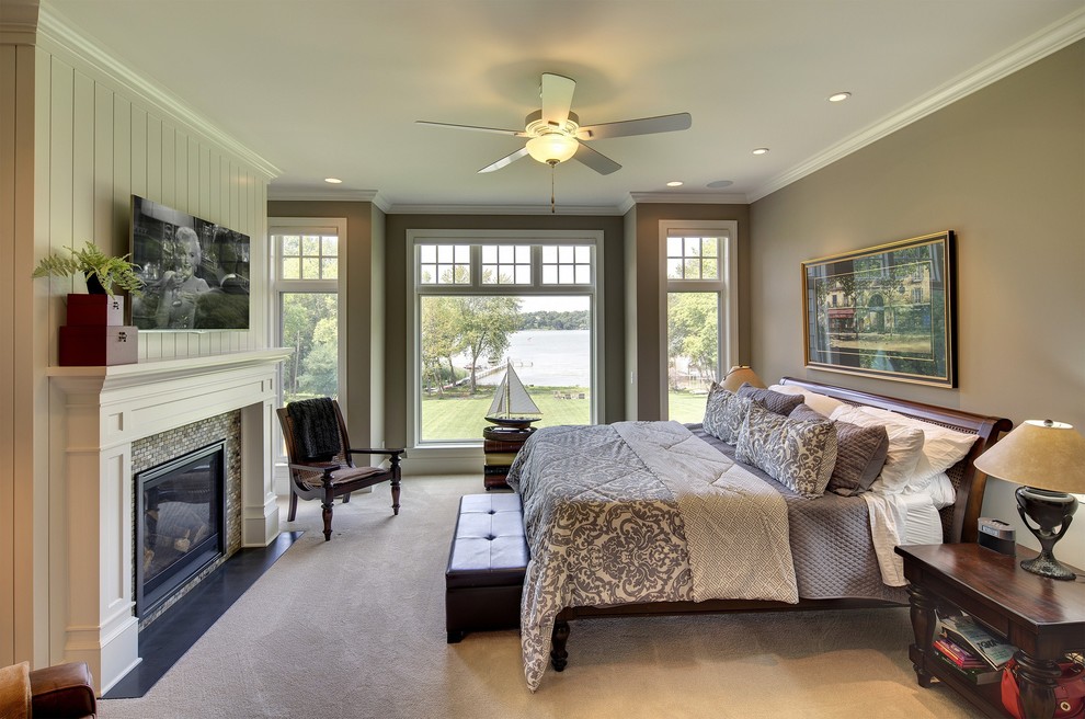 Large traditional master bedroom in Minneapolis with beige walls, carpet, a standard fireplace, a tile fireplace surround and beige floor.
