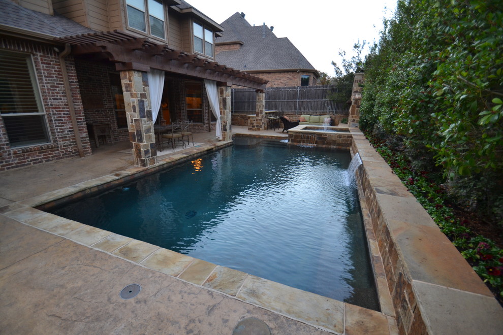 Photo of a small transitional backyard custom-shaped pool in Dallas with a water feature and stamped concrete.