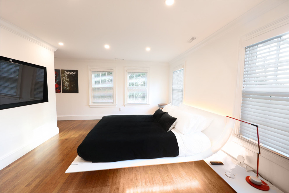 Modelo de dormitorio principal contemporáneo grande con paredes blancas y suelo de madera en tonos medios