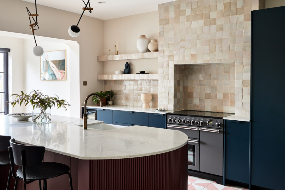 Inredning av ett modernt stort grå grått kök, med släta luckor, blå skåp, bänkskiva i koppar, beige stänkskydd, stänkskydd i keramik, betonggolv, en köksö och rosa golv