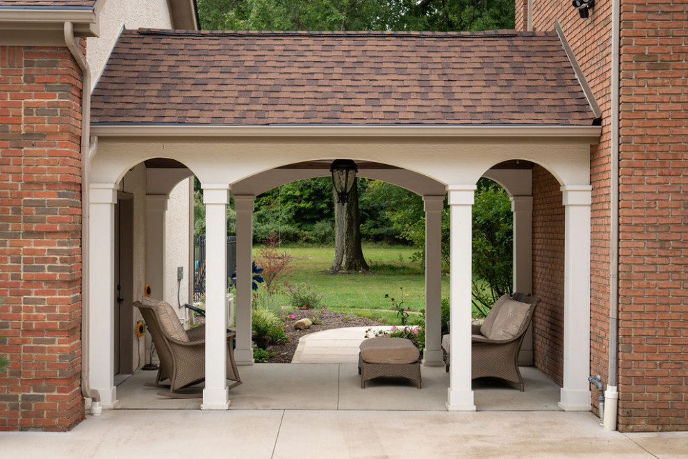 Photo of a medium sized traditional side veranda in Columbus with with columns, concrete slabs and a pergola.