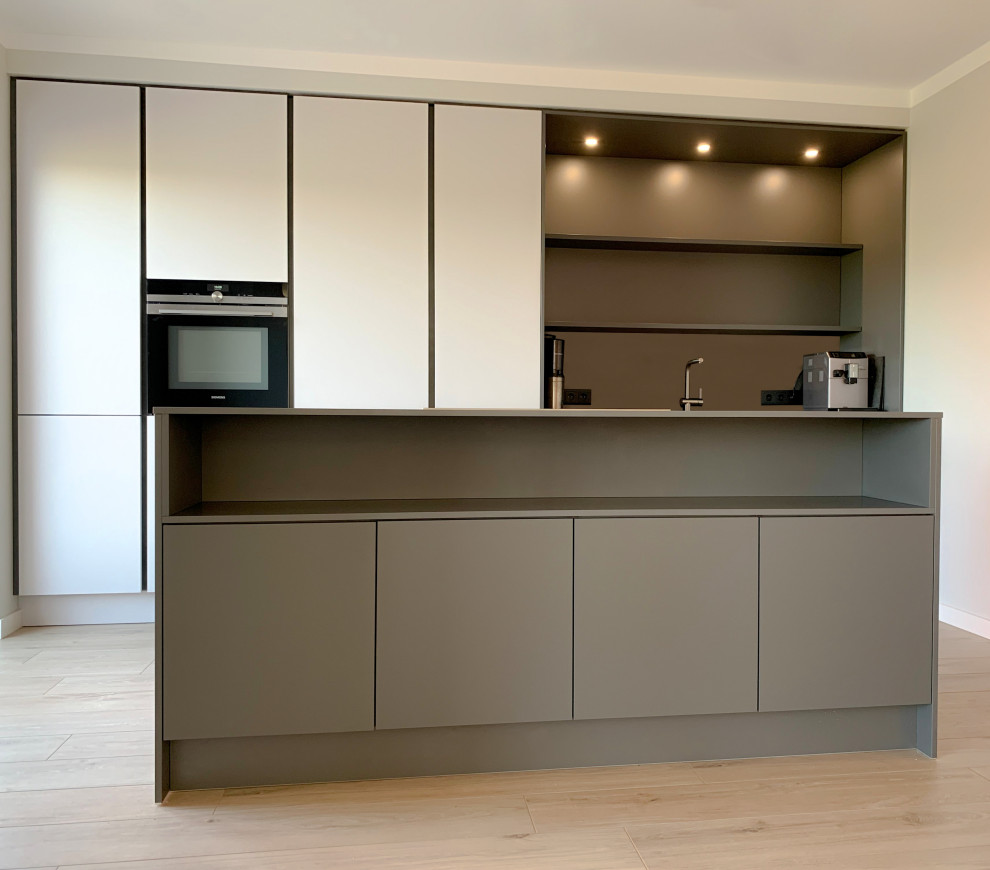 This is an example of a mid-sized modern galley open plan kitchen in Bremen with a single-bowl sink, flat-panel cabinets, grey cabinets, laminate benchtops, grey splashback, stainless steel appliances, painted wood floors, with island and grey benchtop.