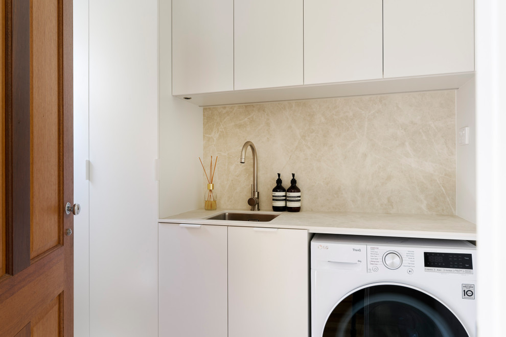 Inspiration for a small scandinavian single-wall dedicated laundry room in Perth with an undermount sink, flat-panel cabinets, white cabinets, quartz benchtops, beige splashback, porcelain splashback, white walls, porcelain floors, a side-by-side washer and dryer, brown floor and beige benchtop.