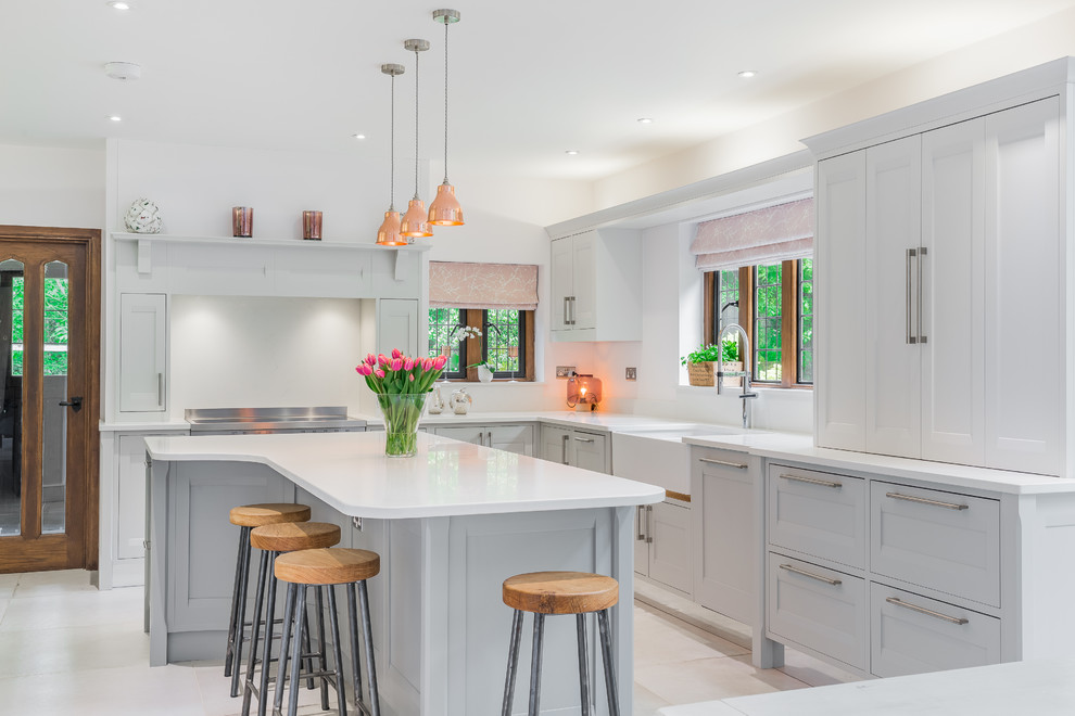 This is an example of a mid-sized transitional l-shaped kitchen in Hertfordshire with recessed-panel cabinets, blue cabinets, quartzite benchtops, a peninsula and white floor.