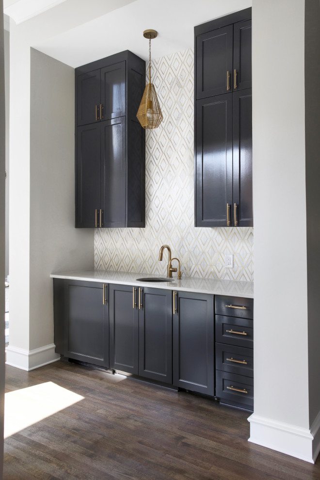 Inspiration for a small transitional single-wall wet bar in Dallas with an undermount sink, shaker cabinets, black cabinets, quartzite benchtops, white splashback, marble splashback, medium hardwood floors, brown floor and grey benchtop.