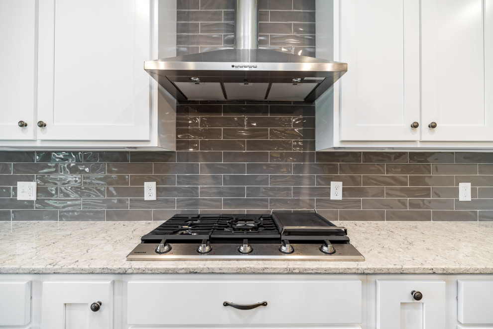 Transitional kitchen photo with shaker cabinets, white cabinets, quartz countertops, gray backsplash, subway tile backsplash, stainless steel appliances and gray countertops