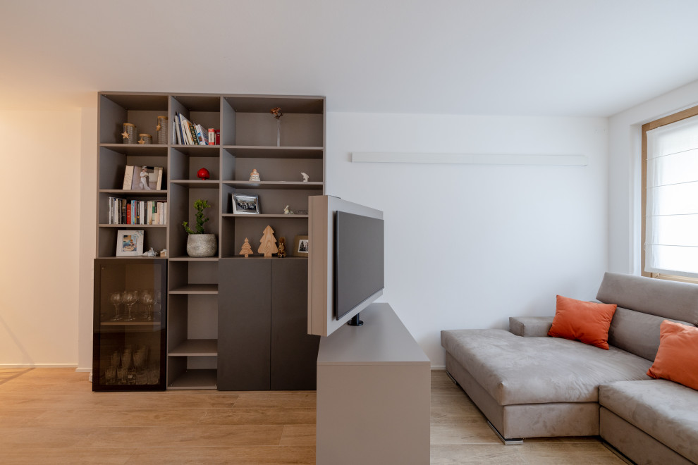 Exempel på ett stort modernt allrum med öppen planlösning, med ett bibliotek, vita väggar, ljust trägolv, en fristående TV och beiget golv