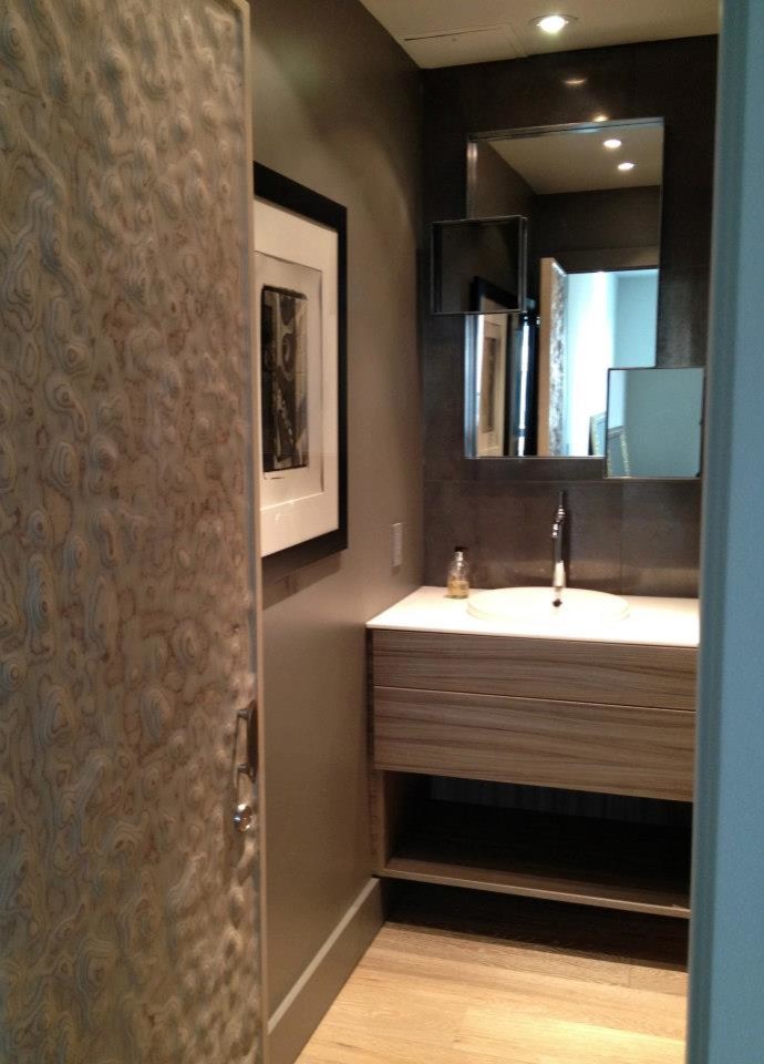 Inspiration for a contemporary powder room in Toronto with flat-panel cabinets, light wood cabinets and solid surface benchtops.