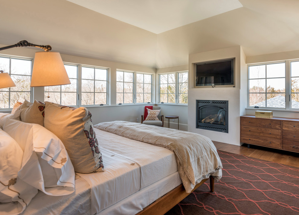 Inspiration for a mid-sized transitional master medium tone wood floor bedroom remodel in New York with beige walls, a standard fireplace and a plaster fireplace