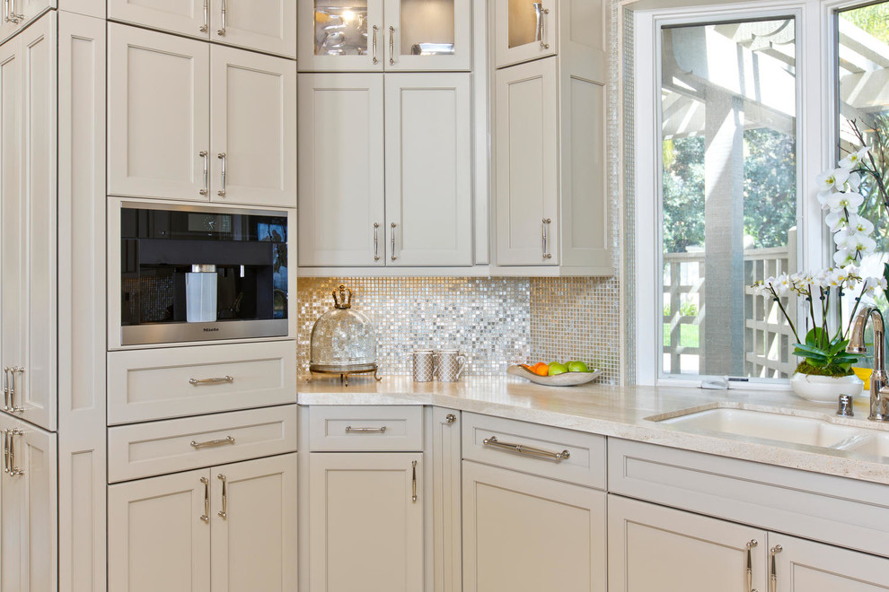 Inspiration for a mid-sized transitional l-shaped open plan kitchen in Denver with an undermount sink, recessed-panel cabinets, beige cabinets, limestone benchtops, beige splashback, glass tile splashback, stainless steel appliances, travertine floors and with island.