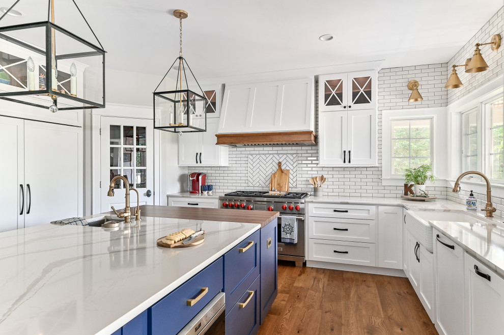ミルウォーキーにある高級な巨大なトランジショナルスタイルのおしゃれなキッチン (エプロンフロントシンク、シェーカースタイル扉のキャビネット、青いキャビネット、珪岩カウンター、白いキッチンパネル、サブウェイタイルのキッチンパネル、パネルと同色の調理設備、クッションフロア、茶色い床、白いキッチンカウンター) の写真