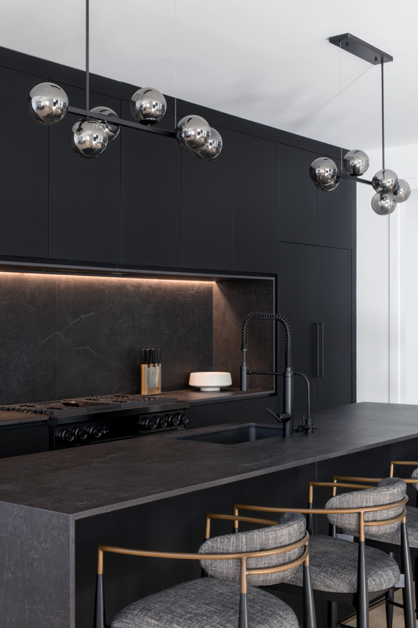 Пример оригинального дизайна: большая параллельная кухня-гостиная в стиле модернизм с врезной мойкой, плоскими фасадами, черными фасадами, черным фартуком, черной техникой, светлым паркетным полом, островом и черной столешницей