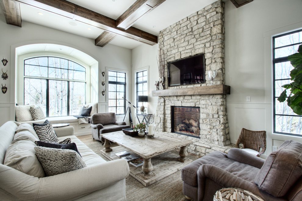 This is an example of a large transitional enclosed family room in Calgary with grey walls, medium hardwood floors, a standard fireplace, a stone fireplace surround, a wall-mounted tv and brown floor.