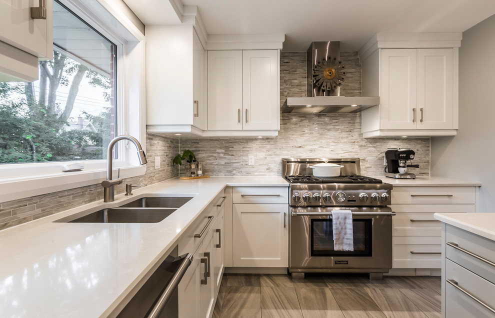 Mid-sized transitional l-shaped porcelain tile and gray floor eat-in kitchen photo with an undermount sink, shaker cabinets, white cabinets, quartz countertops, multicolored backsplash, matchstick tile backsplash, stainless steel appliances and an island