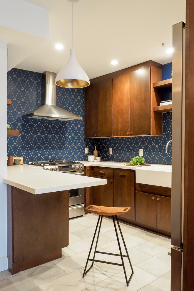This is an example of a small contemporary u-shaped separate kitchen in San Francisco with a farmhouse sink, flat-panel cabinets, dark wood cabinets, blue splashback, ceramic splashback, stainless steel appliances, ceramic floors, a peninsula, beige floor and white benchtop.