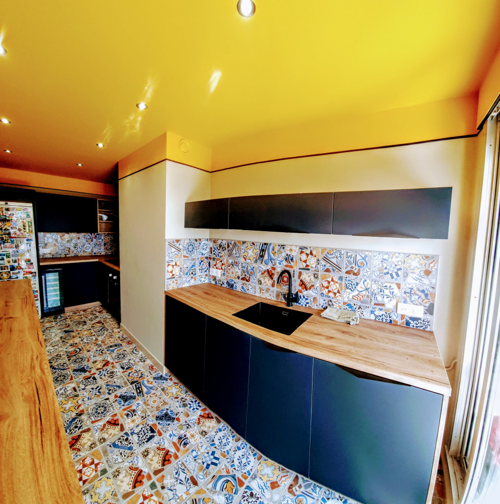 Bild på ett avskilt, mycket stort funkis beige beige l-kök, med en enkel diskho, luckor med profilerade fronter, blå skåp, träbänkskiva, flerfärgad stänkskydd, stänkskydd i keramik, integrerade vitvaror, klinkergolv i keramik och flerfärgat golv