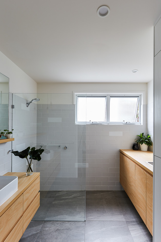 Photo of a small beach style bathroom in Gold Coast - Tweed with white tile, gray tile, subway tile, a vessel sink, wood benchtops, grey floor, flat-panel cabinets, medium wood cabinets, a curbless shower, beige walls, an open shower and brown benchtops.