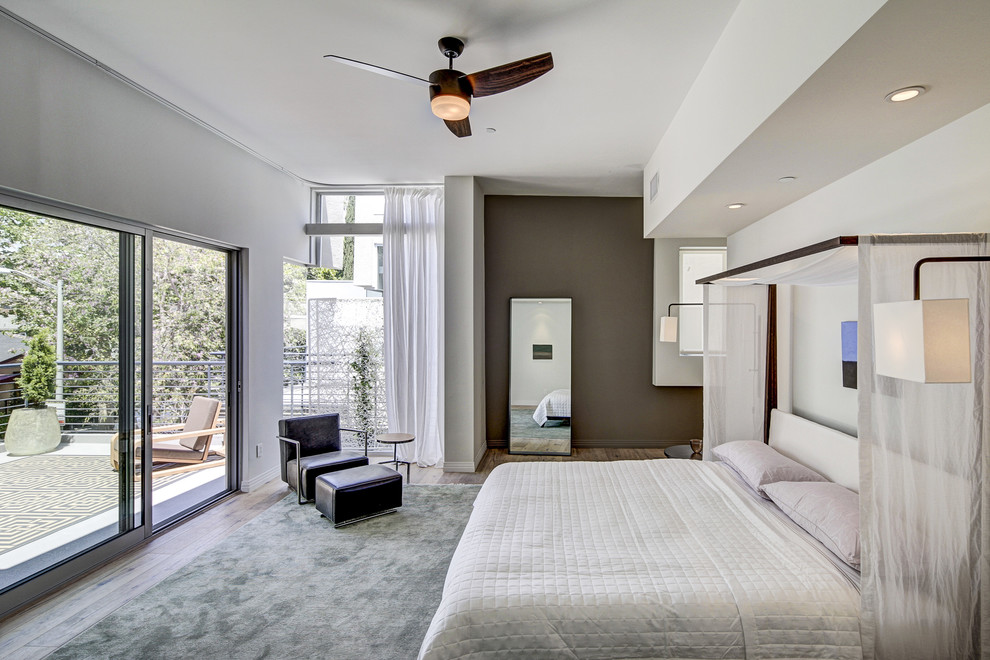 This is an example of a contemporary master bedroom in Los Angeles with grey walls, medium hardwood floors and no fireplace.