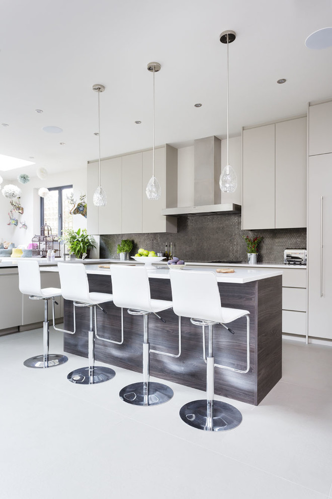 This is an example of a contemporary eat-in kitchen in London with a drop-in sink, grey cabinets, quartzite benchtops, metallic splashback, stainless steel appliances and with island.