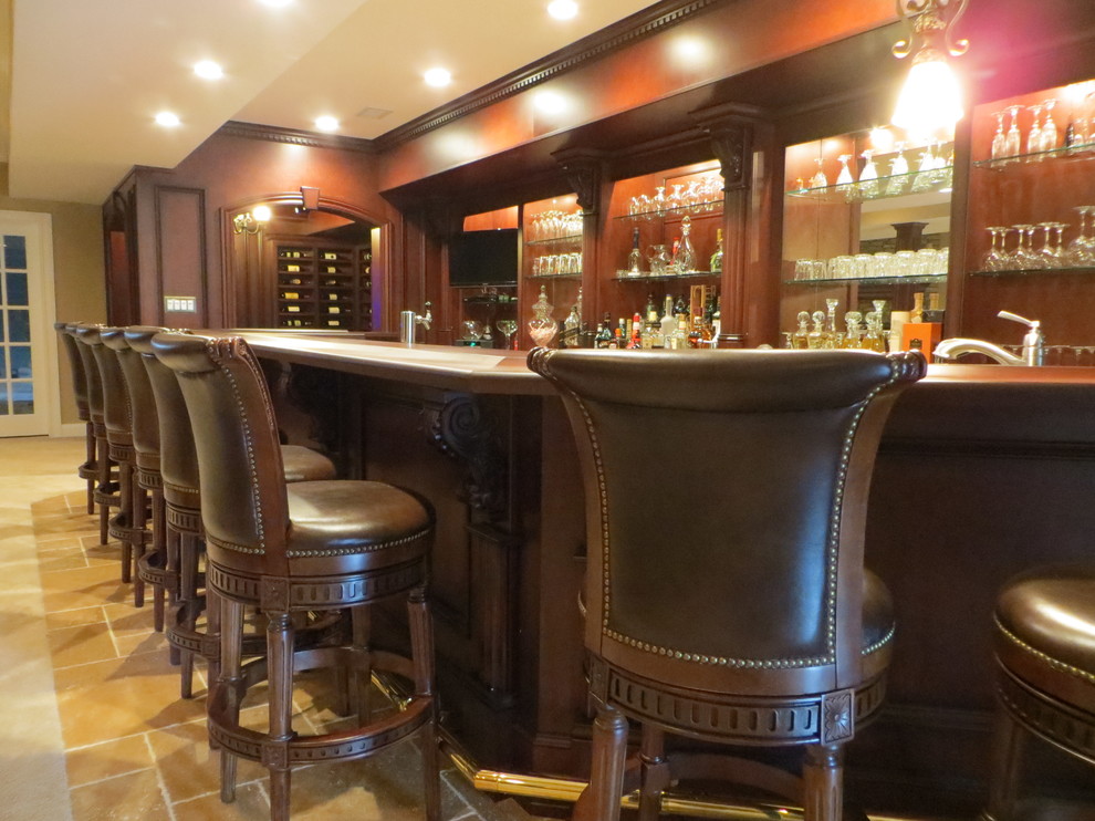 Large traditional u-shaped seated home bar in Philadelphia with medium wood cabinets, wood benchtops, mirror splashback, travertine floors and beige floor.