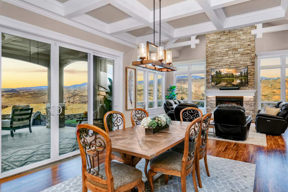 Mid-sized country open plan dining in Boise with medium hardwood floors, brown floor, beige walls, a standard fireplace and a stone fireplace surround.