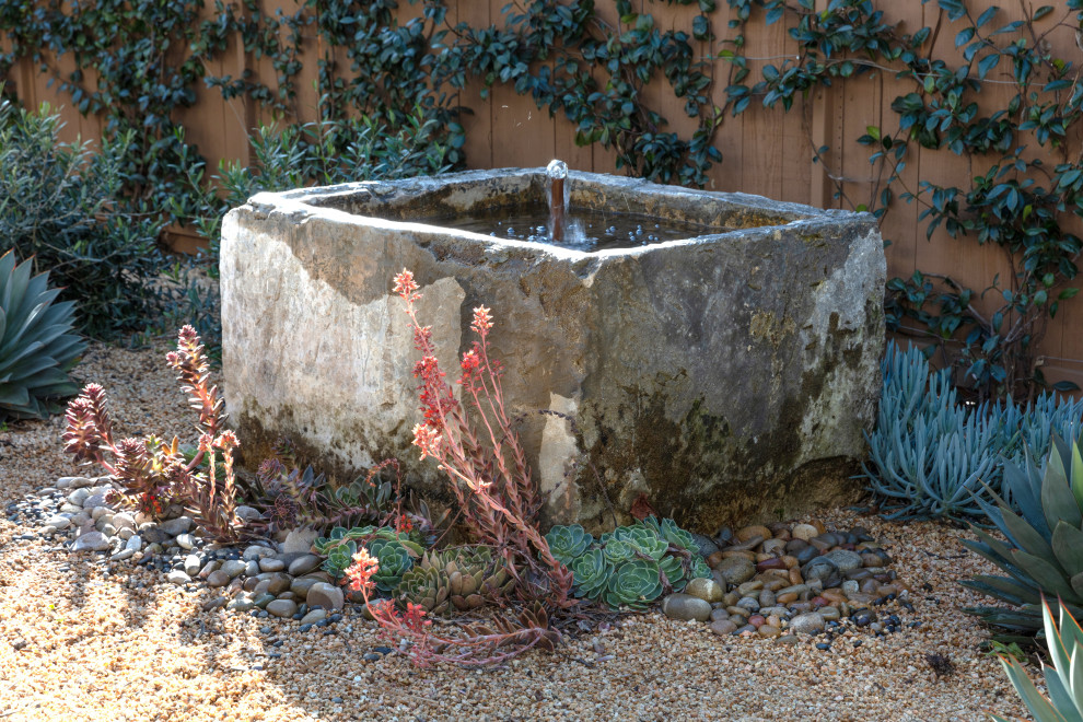 This is an example of a mid-sized mediterranean drought-tolerant backyard water fountain landscape in Santa Barbara.
