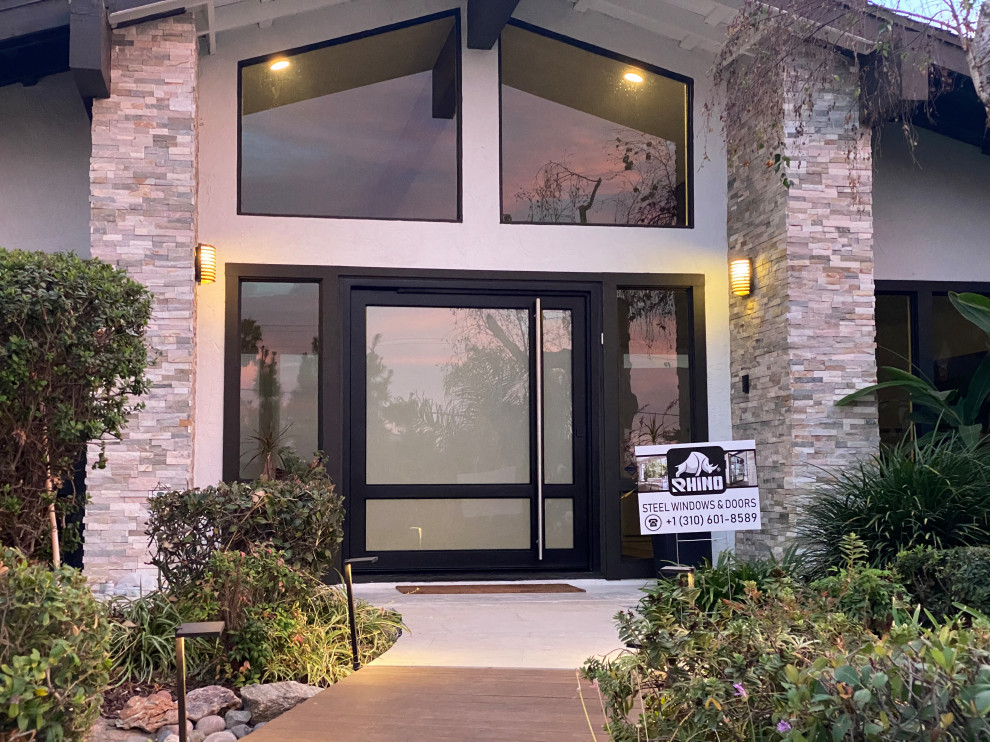 Design ideas for a large contemporary front door in San Diego with beige walls, a pivot front door, a black front door and beige floors.